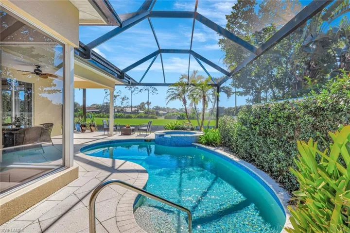 View of swimming pool featuring glass enclosure, an in ground hot tub, and a patio