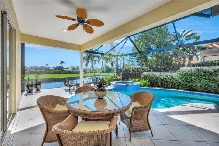 View of swimming pool with a patio area, ceiling fan, a water view, and glass enclosure