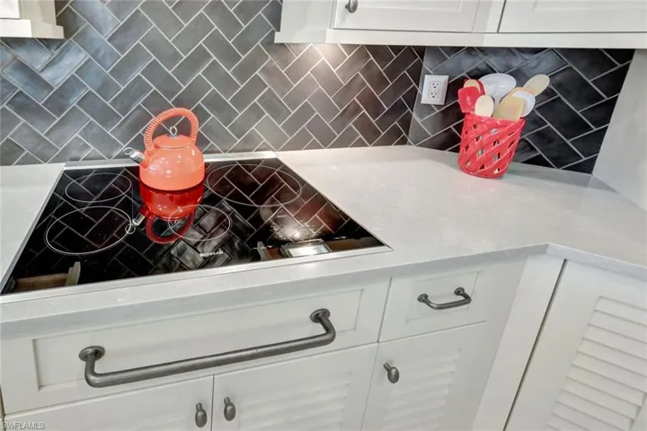 Kitchen featuring decorative backsplash, white cabinets, and invection cook top