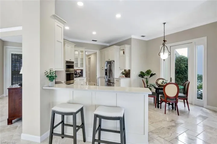 Kitchen featuring crown molding, decorative light fixtures, a kitchen bar, kitchen peninsula, and stainless steel appliances