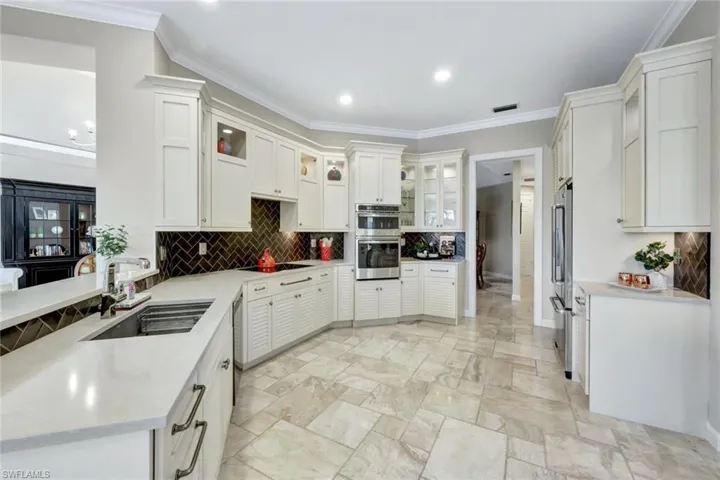 Kitchen featuring crown molding, white cabinetry, sink, and appliances with stainless steel finishes