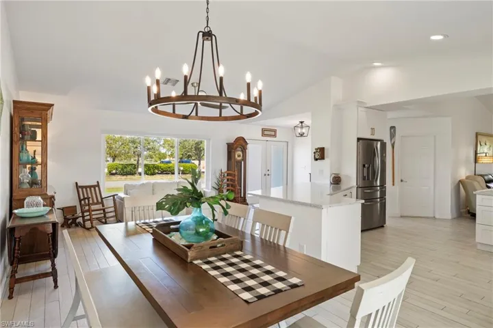 Dining room featuring lofted ceiling, light wood finished floors, french doors, a chandelier, and recessed lighting