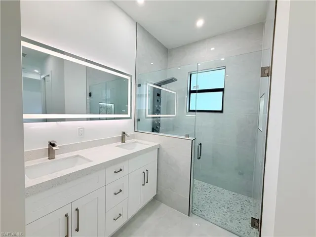 Dual vanity with white cabinetry, light-toned countertops, and brushed nickel faucets