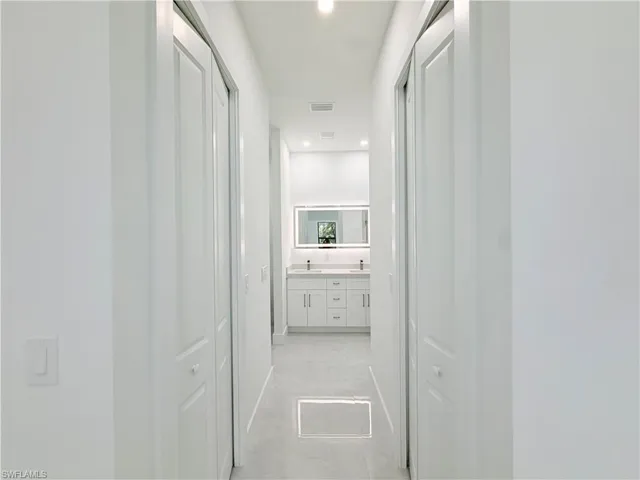Recessed lighting, light gray tile flooring, mirrored medicine cabinet, dual vanity with white cabinetry, and a light-toned countertop