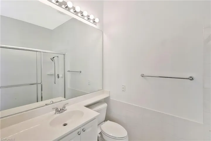 Full bath with tile walls, a wainscoted wall, vanity, and a stall shower