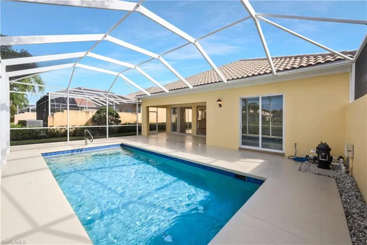 Outdoor pool featuring a sunroom, a patio area, and glass enclosure