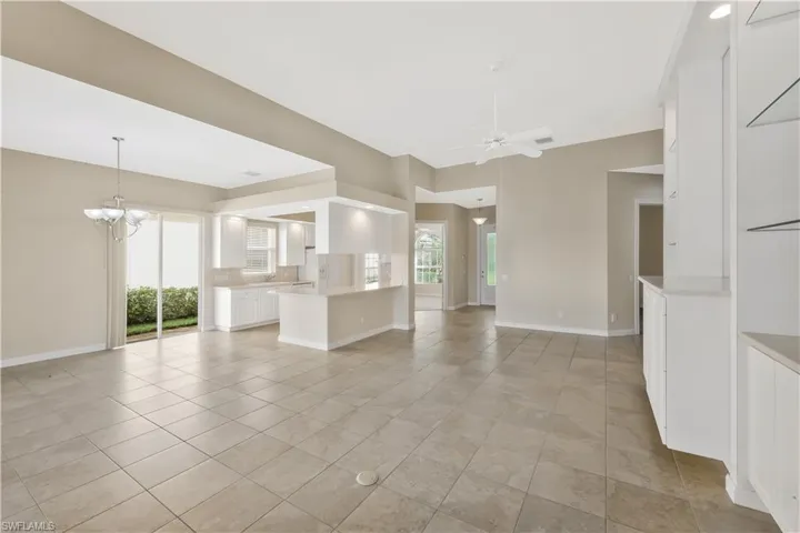 Unfurnished living room featuring a chandelier, a ceiling fan, and light tile patterned floors