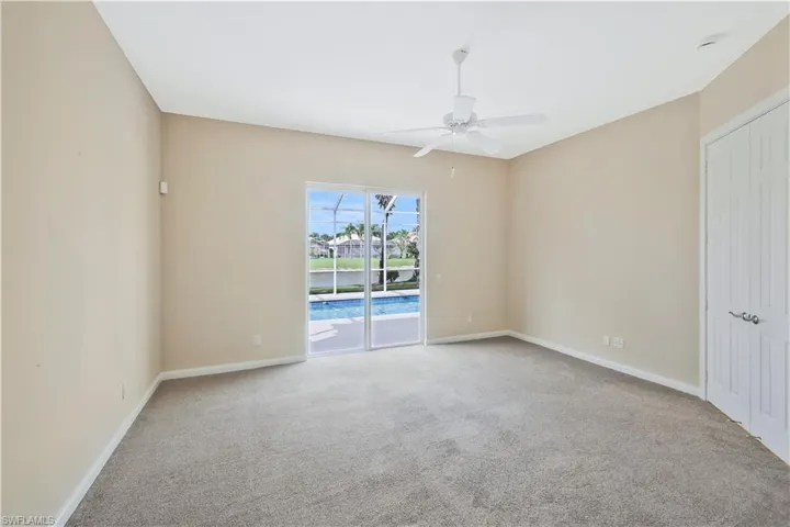 Carpeted spare room featuring ceiling fan and baseboards