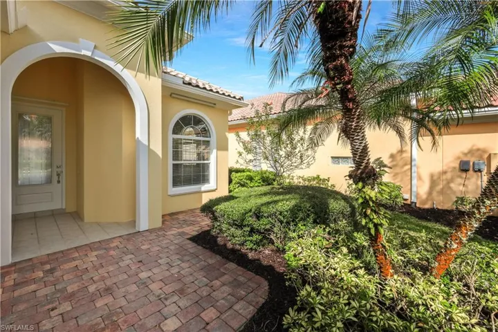 Doorway to property with stucco siding, a tile roof, and a patio area