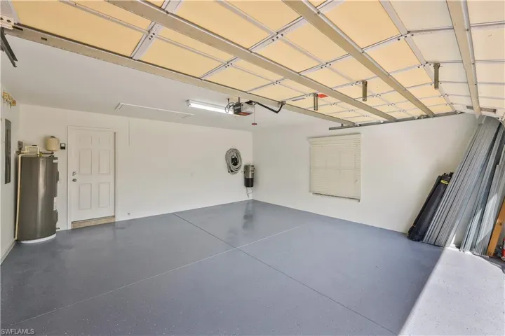 Garage featuring water heater, electric panel, and a garage door opener