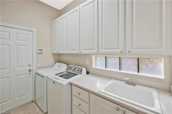 Laundry room with cabinet space, washer and clothes dryer, and light tile patterned floors