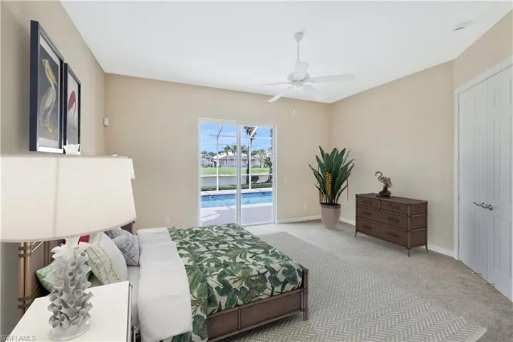 Bedroom with access to exterior, carpet flooring, ceiling fan, and a water view