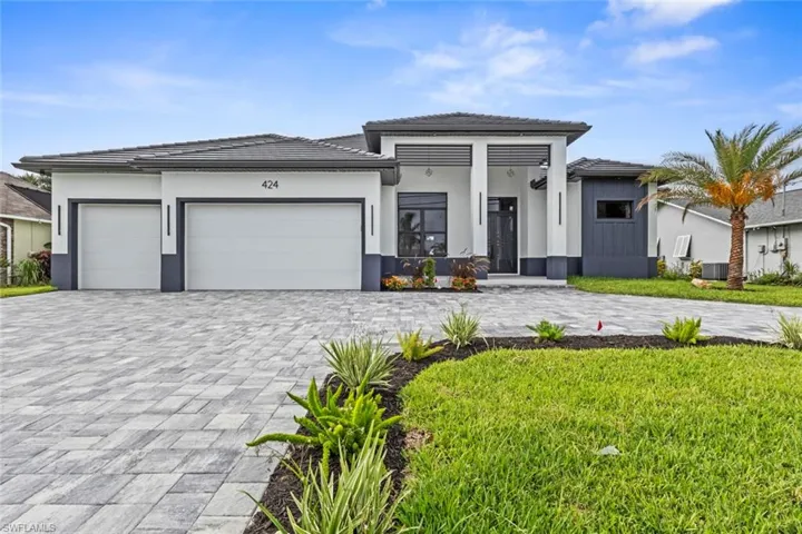 Prairie-style home featuring decorative driveway, an attached garage, a tiled roof, and stucco siding