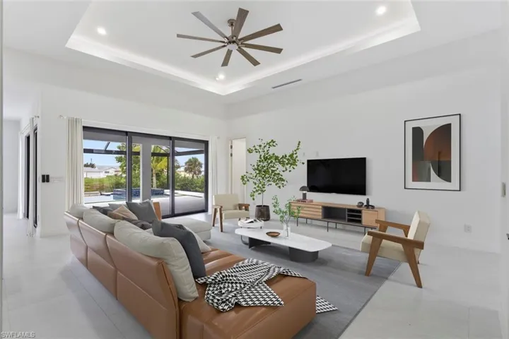 Living area with a tray ceiling, ceiling fan, recessed lighting, and a high ceiling