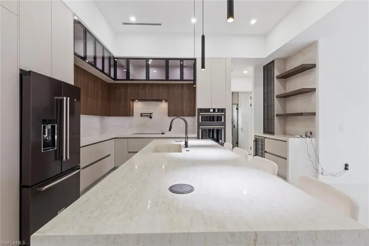 Kitchen with black appliances, modern cabinets, open shelves, a large island, and wine cooler