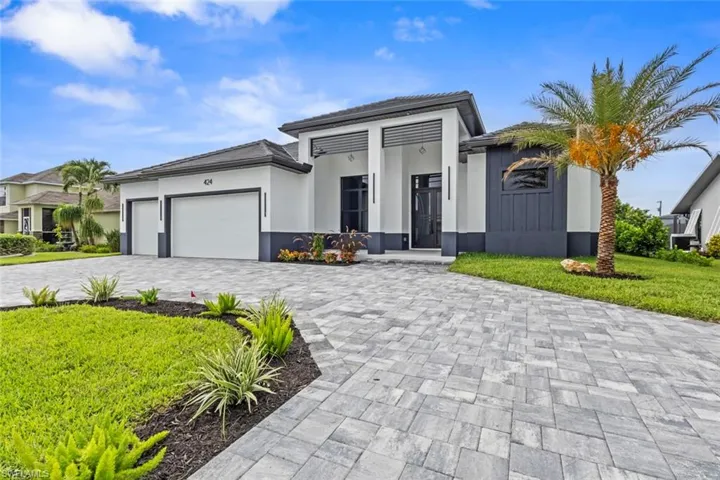 View of front facade featuring decorative driveway, an attached garage, a front lawn, and a tile roof