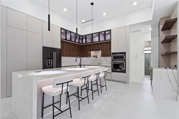 Kitchen featuring black appliances, open shelves, modern cabinets, a breakfast bar, and decorative backsplash