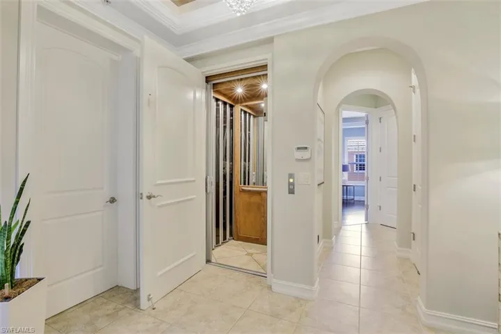 Hall featuring light tile flooring and crown molding