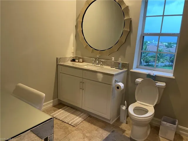 Bathroom with tile flooring, vanity with extensive cabinet space, and toilet