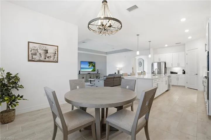 Dining space with a raised ceiling, arched walkways, recessed lighting, and a chandelier