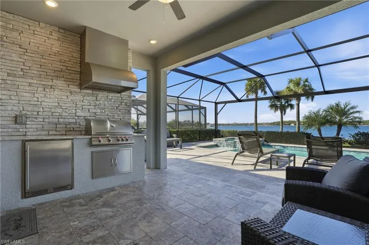 View of patio / terrace with a sunroom, glass enclosure, a ceiling fan, a water view, and a pool with connected hot tub