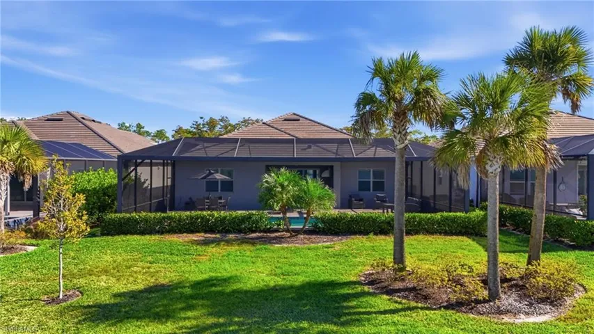 Back of house with a sunroom, a lanai, a lawn, and a swimming pool