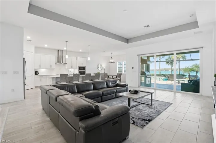 Living area featuring a raised ceiling, a water view, and recessed lighting