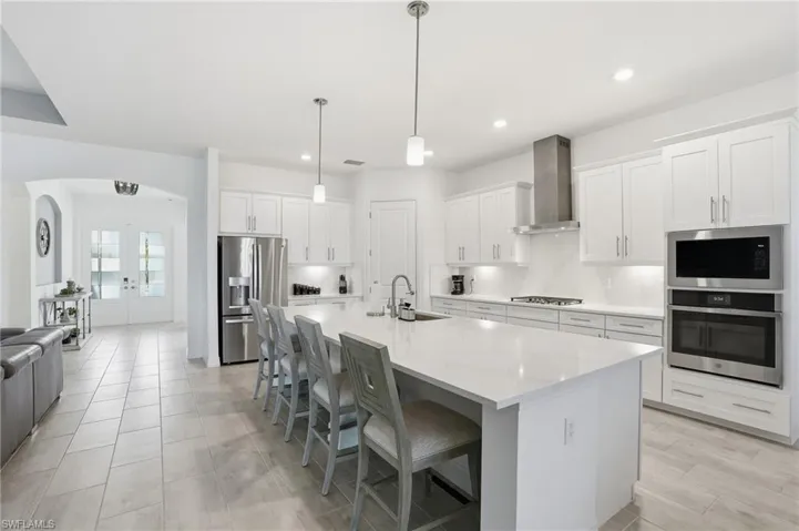 Kitchen with french doors, a breakfast bar area, appliances with stainless steel finishes, white cabinets, and arched walkways
