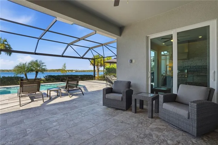 View of patio / terrace with a sunroom, an outdoor pool, glass enclosure, a water view, and a ceiling fan