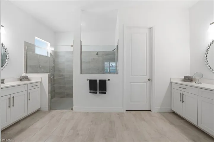 Full bath with two vanities, a shower stall, and wood tiled floors
