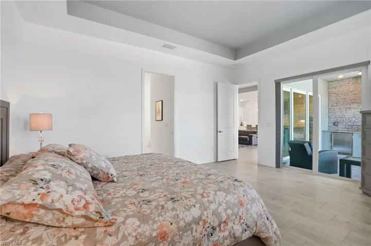 Bedroom featuring light wood-type flooring, a raised ceiling, and access to exterior