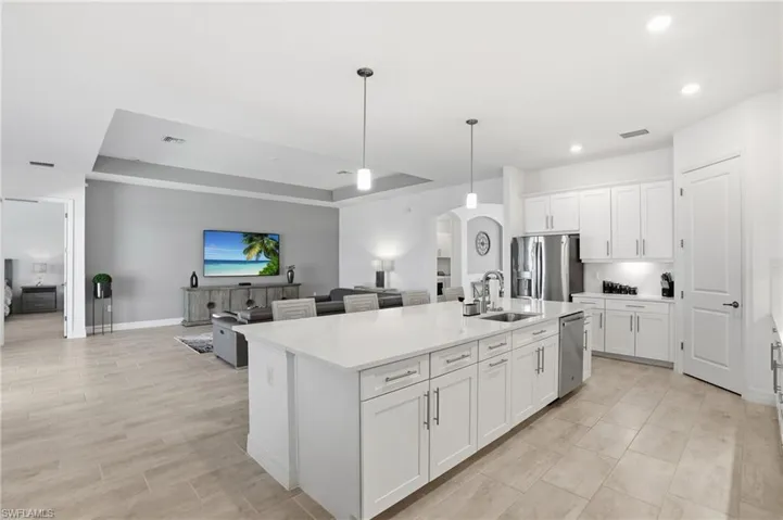 Kitchen featuring hanging light fixtures, arched walkways, white cabinetry, open floor plan, and a tray ceiling