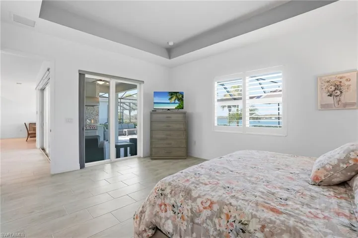 Bedroom featuring access to exterior, a tray ceiling, and wood finish floors