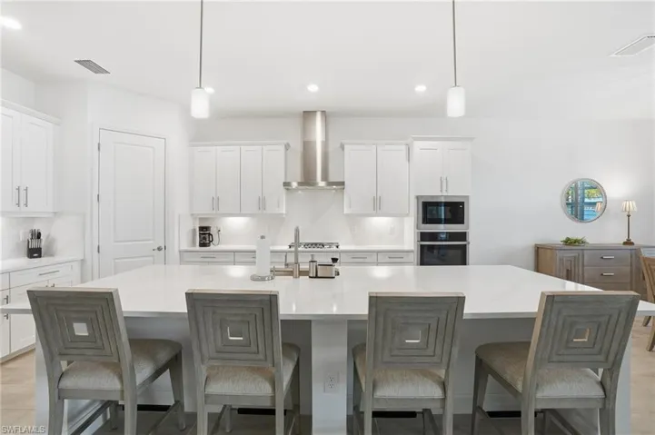 Kitchen featuring white cabinets, pendant lighting, a breakfast bar area, a spacious island, and oven