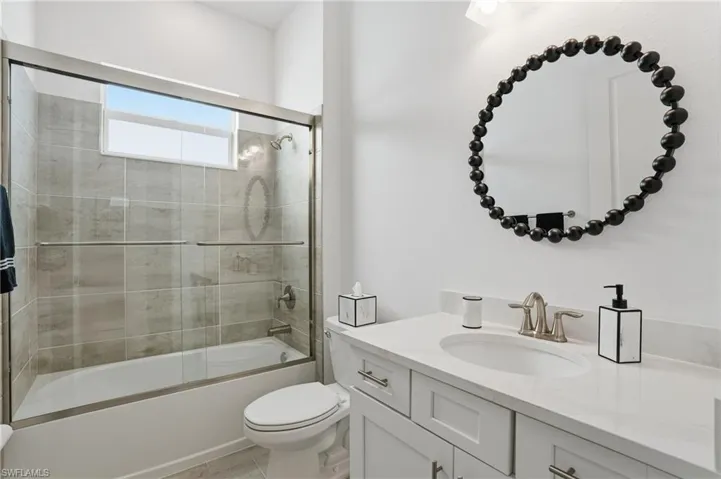 Bathroom with vanity and bath / shower combo with glass door