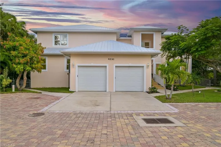 View of front of house featuring stucco siding, driveway, a metal roof, and an attached garage