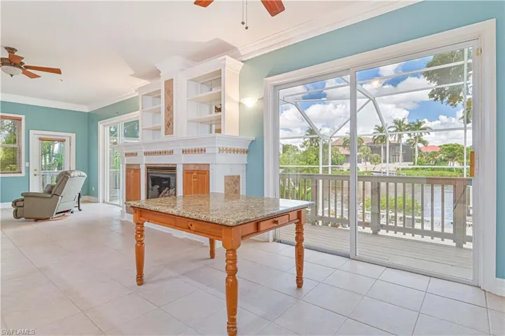 Living area with a ceiling fan, ornamental molding, light tile patterned flooring, a fireplace, and a sunroom