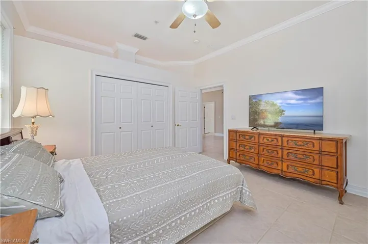 Bedroom featuring ornamental molding, tile patterned floors, a closet, and ceiling fan