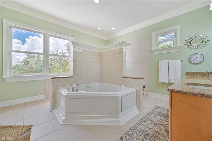 Full bath featuring tile patterned floors, a bath, vanity, plenty of natural light, and crown molding