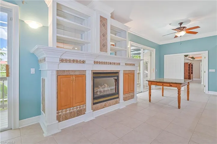 Unfurnished living room featuring a fireplace, ceiling fan, plenty of natural light, crown molding, and light tile patterned flooring