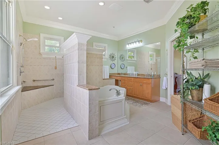 Full bathroom featuring a bath, a walk in shower, vanity, tile patterned floors, and ornamental molding