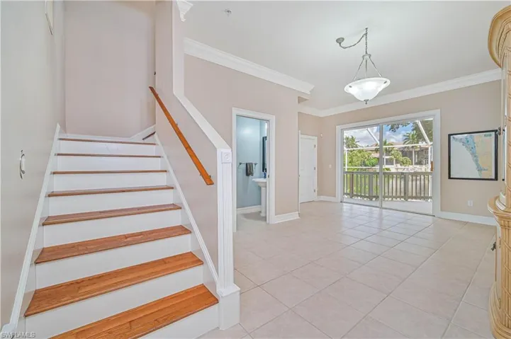 Stairway with crown molding and tile patterned floors