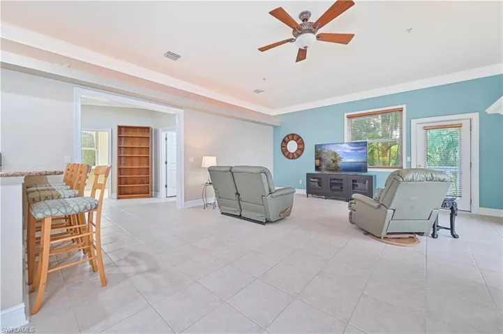 Living area featuring ornamental molding, plenty of natural light, a ceiling fan, and light tile patterned flooring