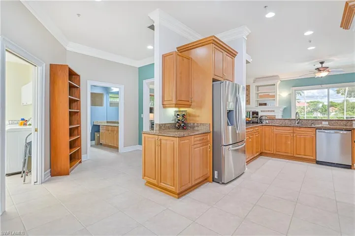 Kitchen featuring stainless steel appliances, ceiling fan, crown molding, dark stone countertops, and light tile patterned flooring