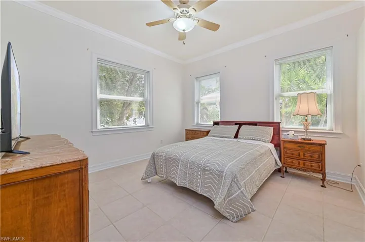 Bedroom featuring light tile patterned floors, ornamental molding, and a ceiling fan