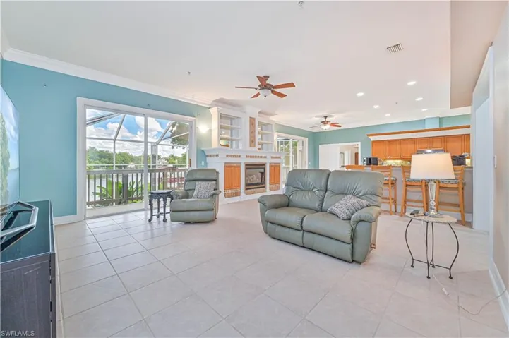 Living area featuring light tile patterned floors, ceiling fan, healthy amount of natural light, ornamental molding, and a fireplace