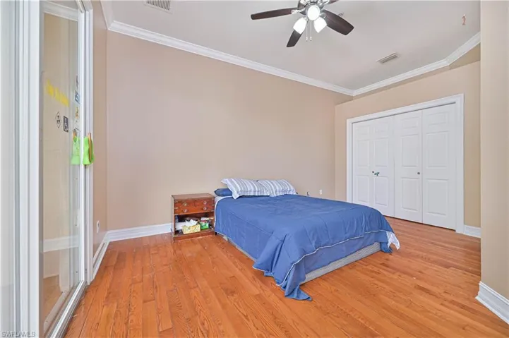 Bedroom featuring light wood-type flooring, ornamental molding, a closet, and a ceiling fan