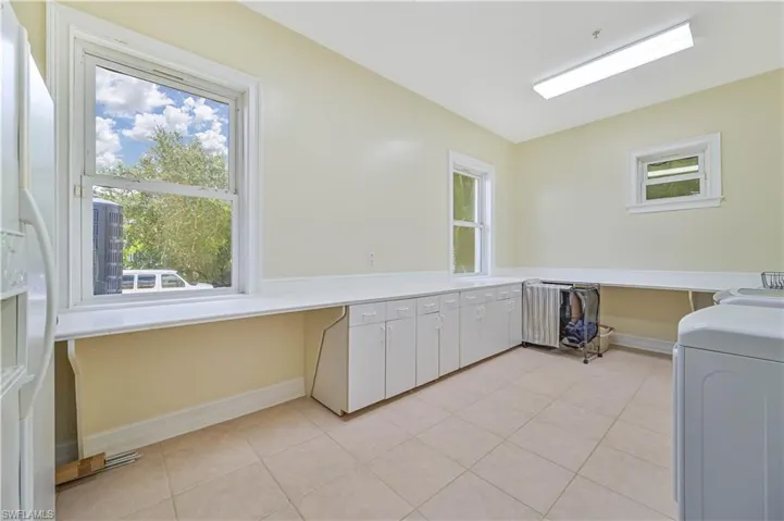 Laundry area with cabinet space and light tile patterned floors