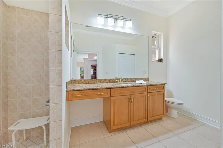 Full bathroom with vanity, tile patterned floors, ornamental molding, and tiled shower
