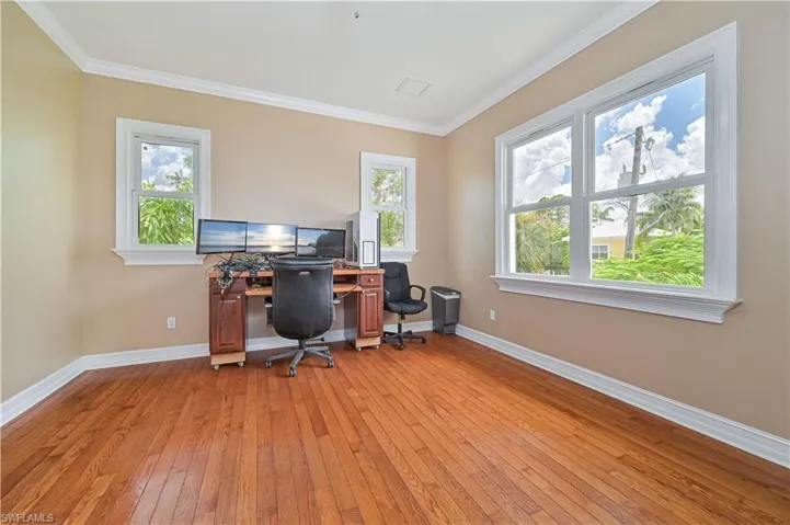Office with light wood-style flooring, ornamental molding, and plenty of natural light